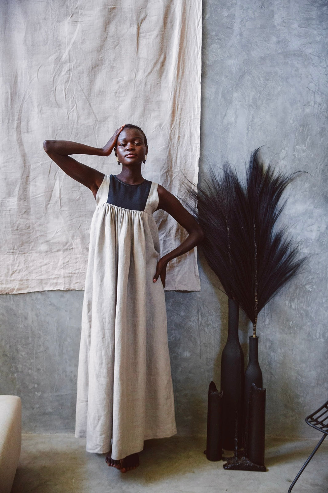 Model wearing Butterfly Linen dress standing next to a black vase with black feather